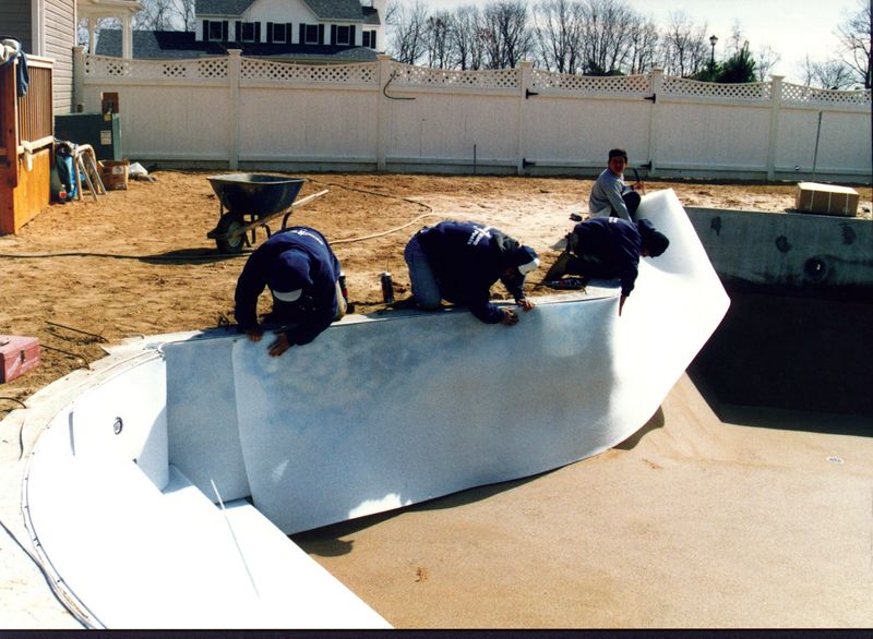 Crew applying wall foam to a concrete pool wall