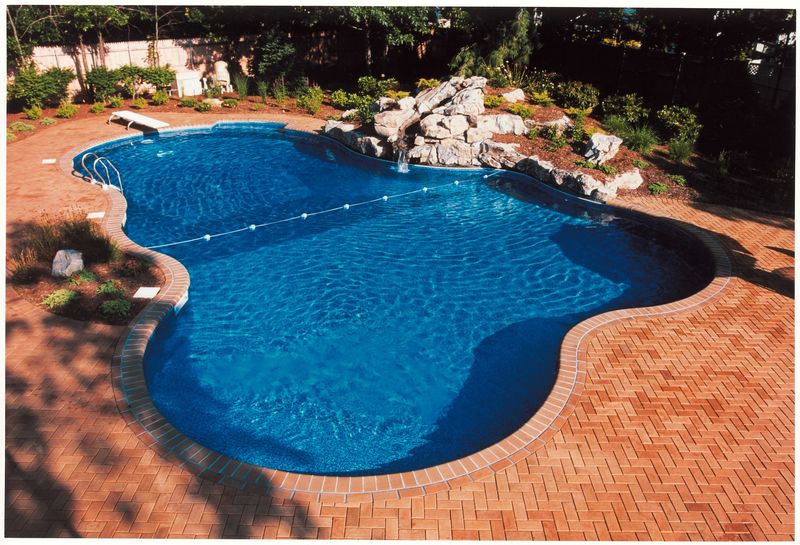 Finished freeform lagoon pool with a brick deck and rock waterfall