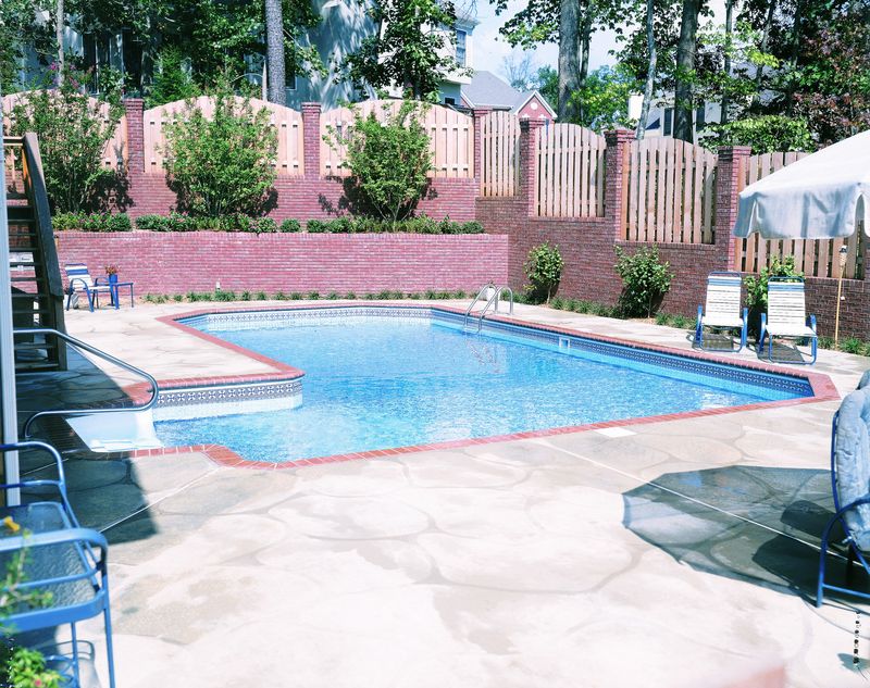 Finished Grecian-L pool with a brick wall behind it