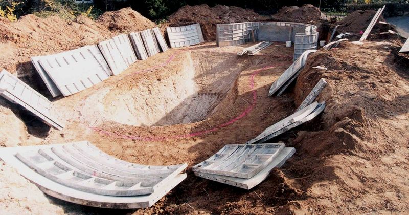 Aluminum pool forms laid out around the excavation before setting