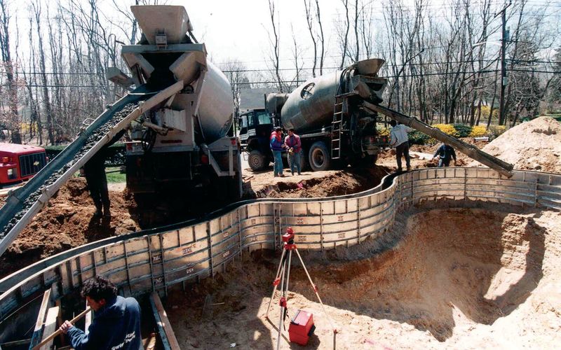 Concrete trucks placing concrete into the pool wall forms