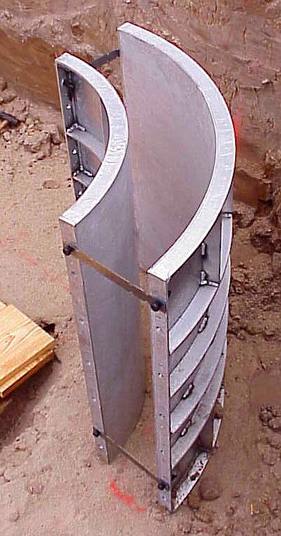 A tall aluminum radius form standing upright on a jobsite