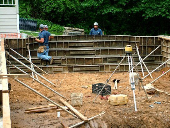Crew squaring and leveling the exterior forms, with a laser level set up inside the pool