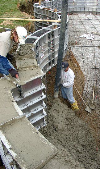 Two crew members placing concrete where the wall meets the floor