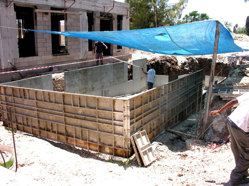 Straight wall forms set for a rectangular pool beneath a shade tarp