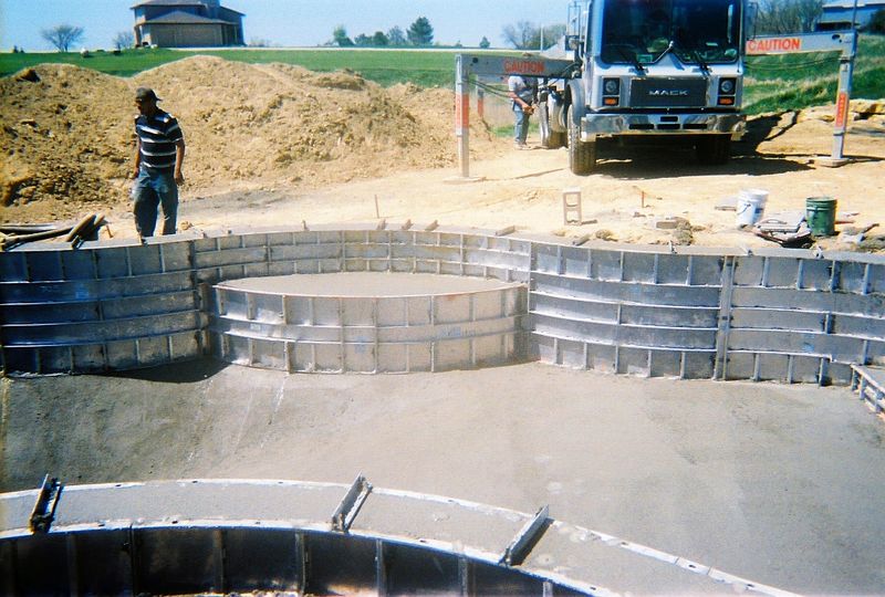 Swimout bench forms set into a pool wall, with a concrete truck behind