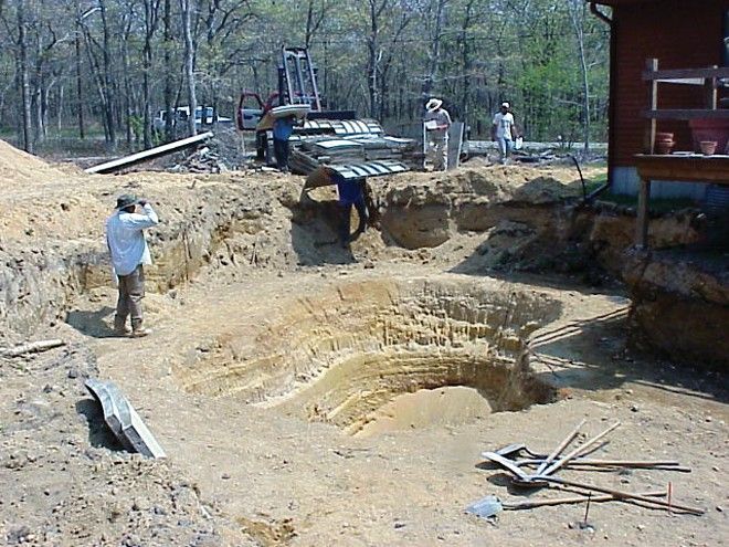 Excavated pool hopper with a crew member checking depth